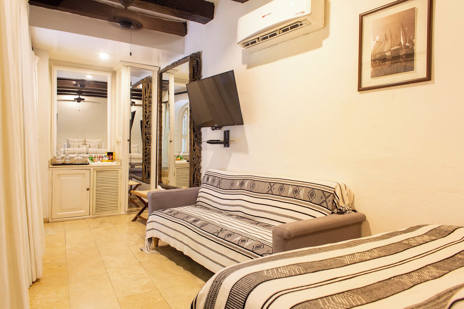 A cozy room with a sofa, a television mounted on the wall, and a framed picture above it.