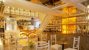 A bar area with white metal chairs and tables, shelves with bottles, and a staircase. - Leones de Alba Hotel Boutique (Cartagena)