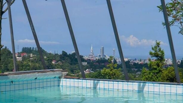 A swimming pool with a view of a cityscape in the background. - Private Villa Guest House (Khelvachauri)