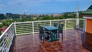 A balcony with a table and chairs, offering a view of a cityscape. - Private Villa Guest House (Khelvachauri)