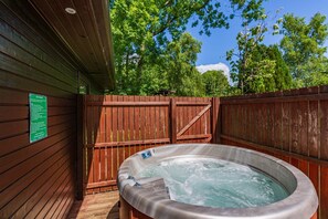 Een hottub in een buitengebied, omgeven door houten wanden en een houten hek.