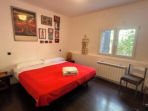 A bedroom with a bed, a radiator, a window, and wall decorations.