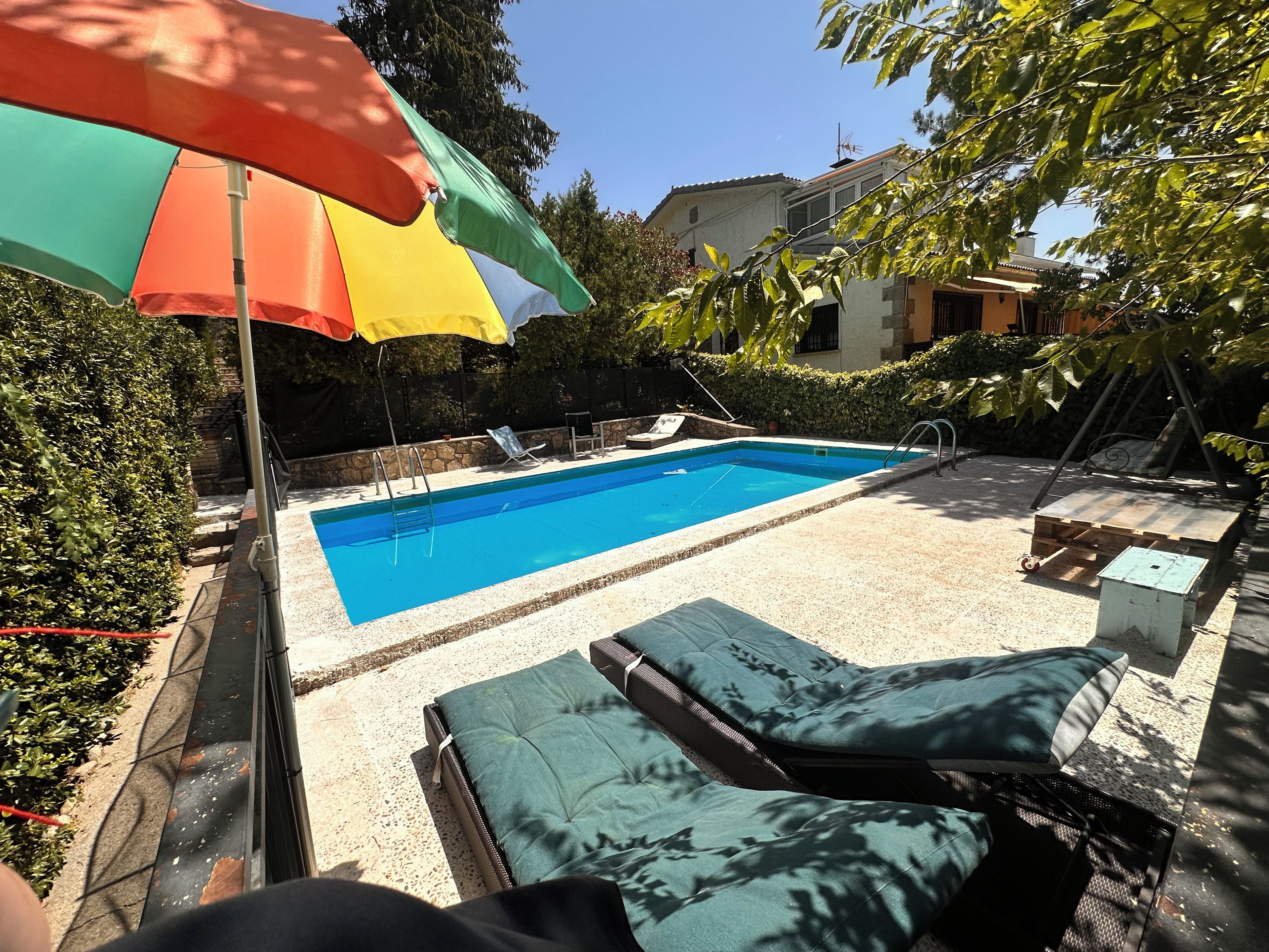 Une piscine avec des chaises longues et un parasol.