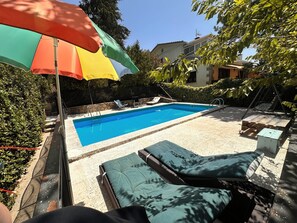 Une piscine avec des chaises longues et un parasol.