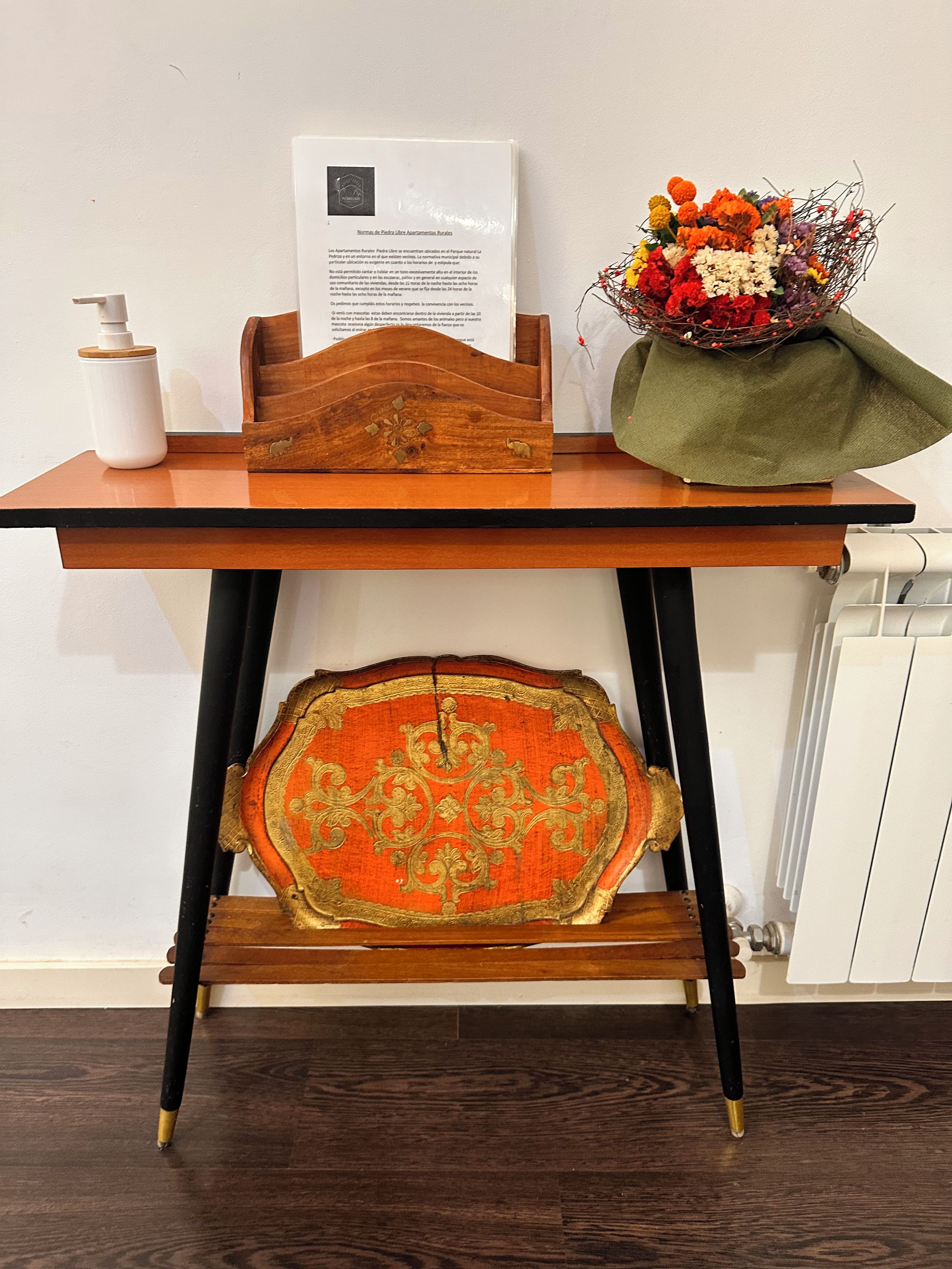 Un bureau en bois sur lequel se trouvent un document, un vase blanc et un bouquet de fleurs.