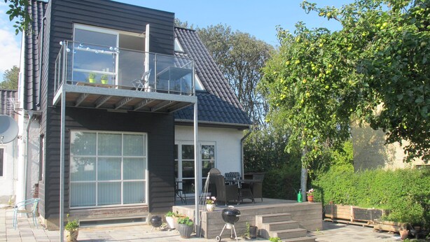 A modern two-story house with a balcony, a patio with outdoor furniture, and a barbecue grill. - Guesthouse Sharon Suite (Aarhus)