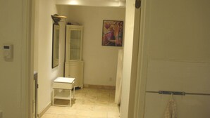 A narrow hallway with a white cabinet, a small table, and a painting on the wall. - Guesthouse Sharon Suite (Aarhus)