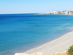 A coastal beach with clear blue waters and a sandy shore.