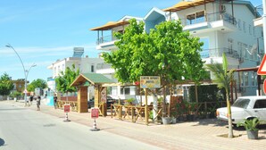 A hotel named 'Likya Apart Hotel' with a signboard, a tree, and a parked car.