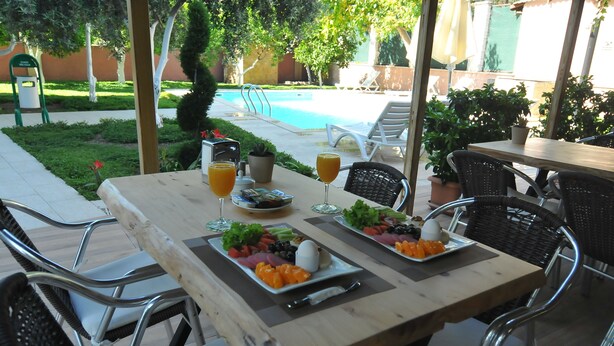 An outdoor dining area with a pool in the background.