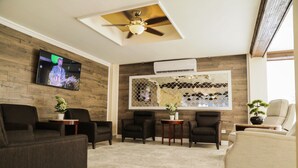 A living room with a ceiling fan, a mounted TV, a decorative wall, and several seating options. - Days Inn by Wyndham Piedras Negras (Piedras Negras)