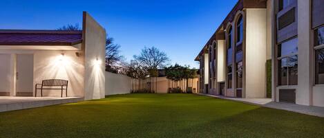 A modern building with a well-maintained lawn and a bench.