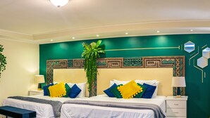 A hotel room with a large bed, two bedside tables, and a green accent wall.