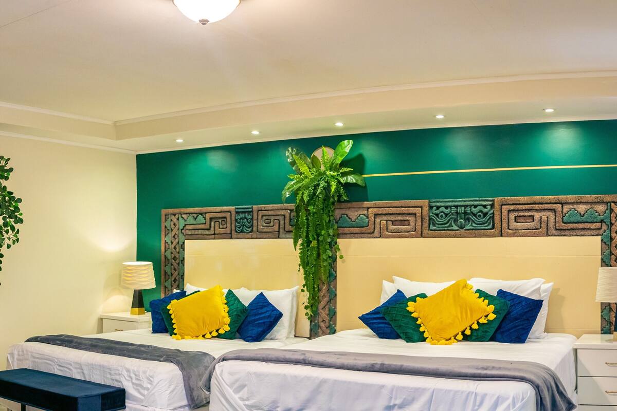A hotel room with a large bed, two bedside tables, and a green accent wall.