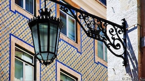 A traditional street lamp with a decorative design, attached to a building with a patterned facade.