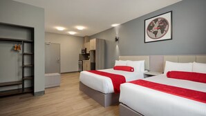 A hotel room with two beds, a kitchenette, and a bathroom.