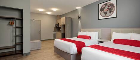 A hotel room with two beds, a wardrobe, a kitchenette, and a framed world map on the wall.