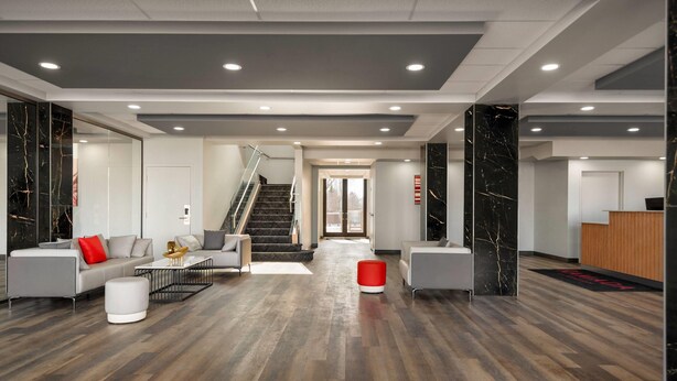 A modern lobby with a staircase, seating area, and reception desk.