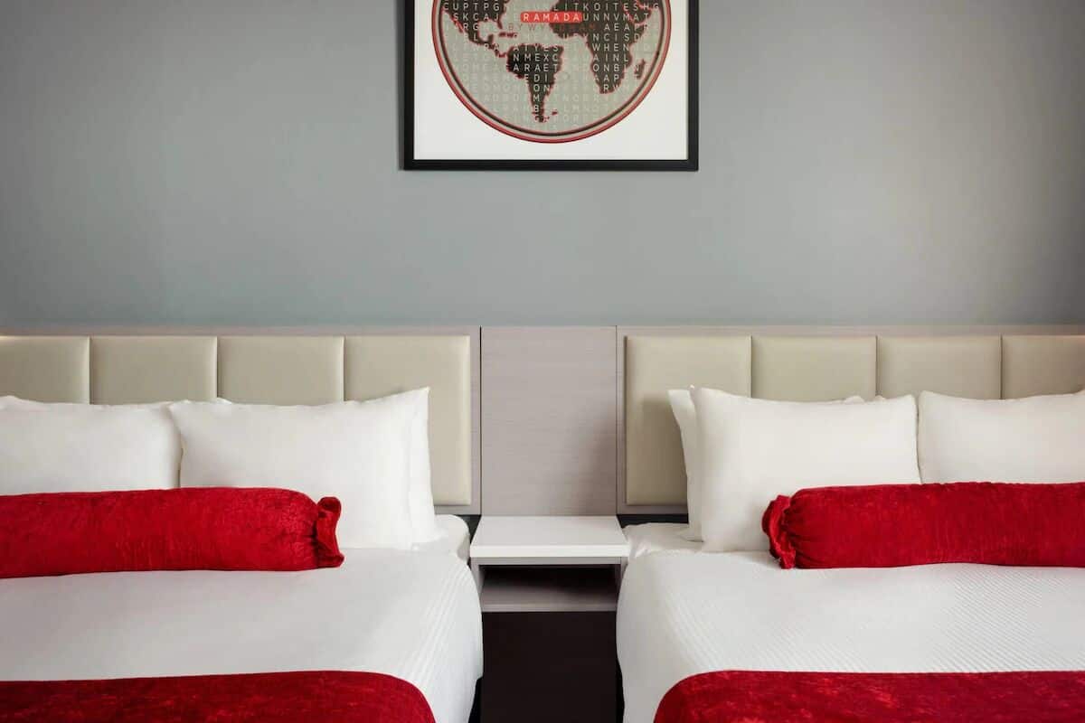 Habitación de hotel con dos camas, un cuadro de un mapa mundial en la pared y una decoración en tonos neutros.