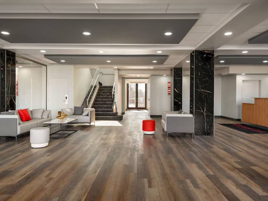 Een moderne lobby met een trap, zithoek en receptiebalie.