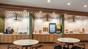 A restaurant with wooden paneling, round tables, and black woven chairs. - Fairfield by Marriott Inn & Suites Pensacola Pine Forest (Pensacola)