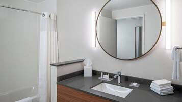Un bagno moderno con una vasca, un lavandino, uno specchio e un portascopevoli.