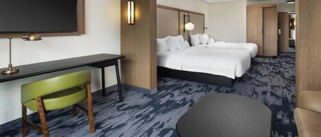 Habitación de hotel con una cama grande, un escritorio con silla, una mesita pequeña y un televisor.