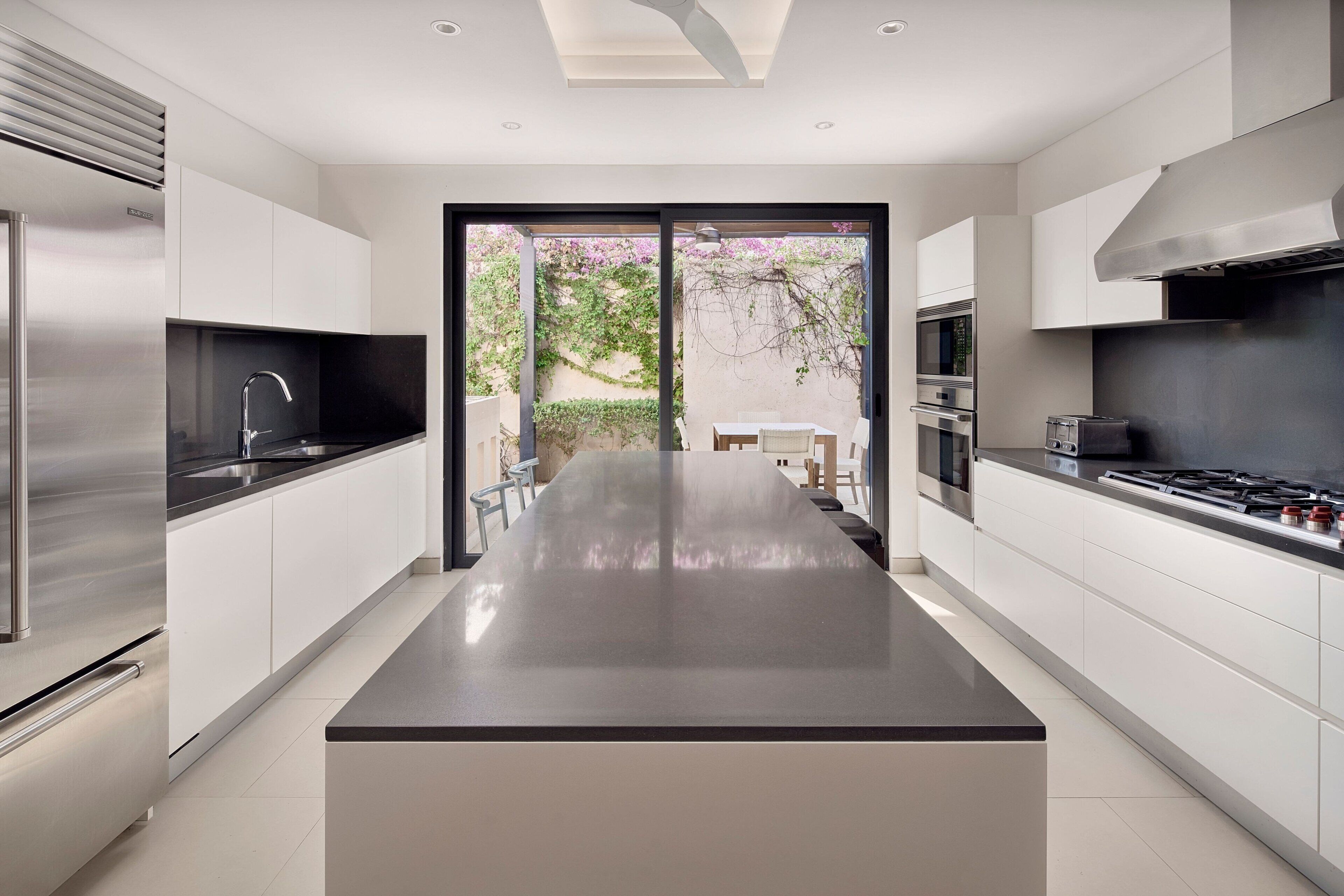 A modern kitchen with a central island, stainless steel appliances, and a view to an outdoor area.