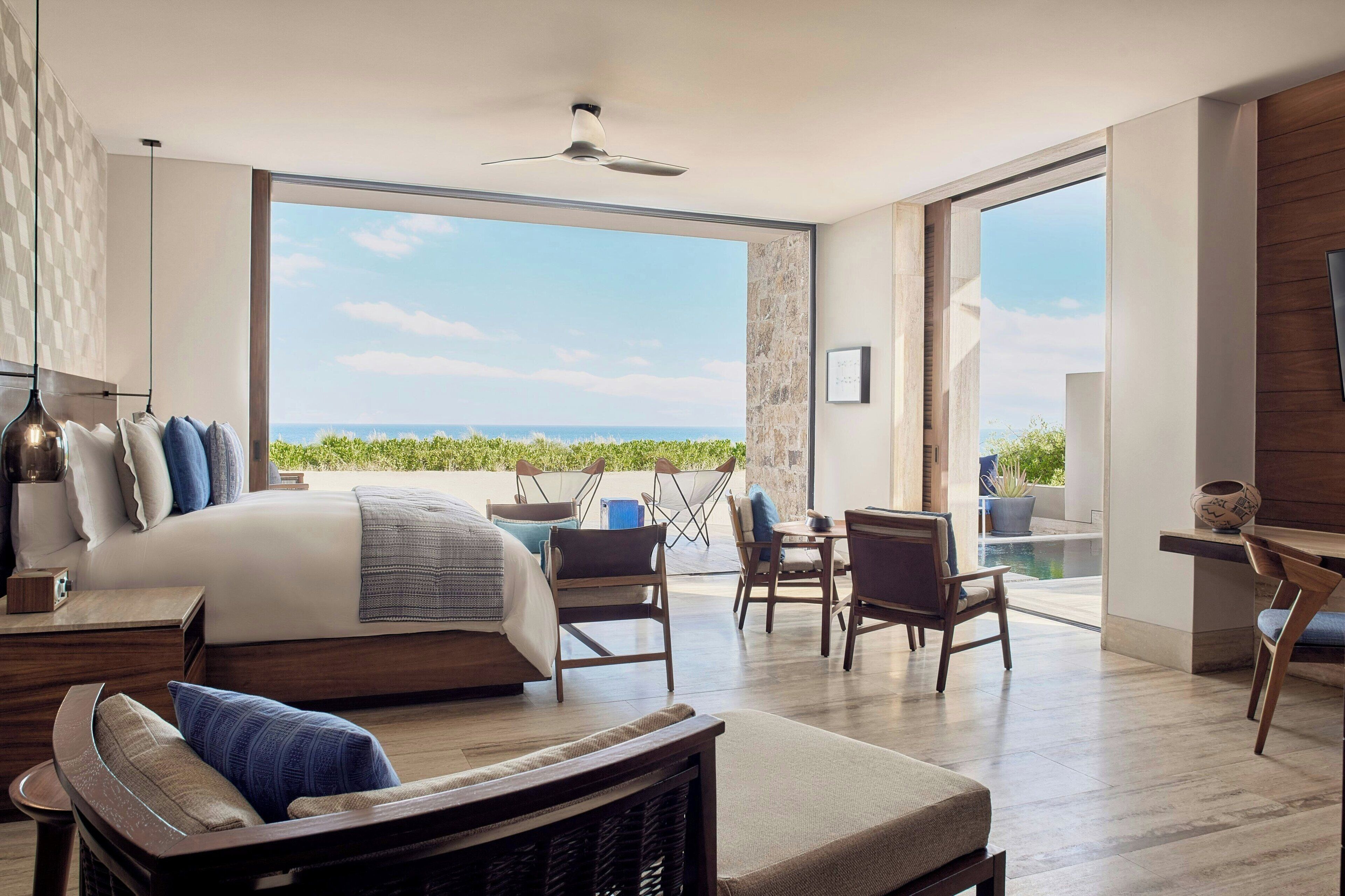 A modern bedroom with a large bed, a balcony with a view, and a dining area.