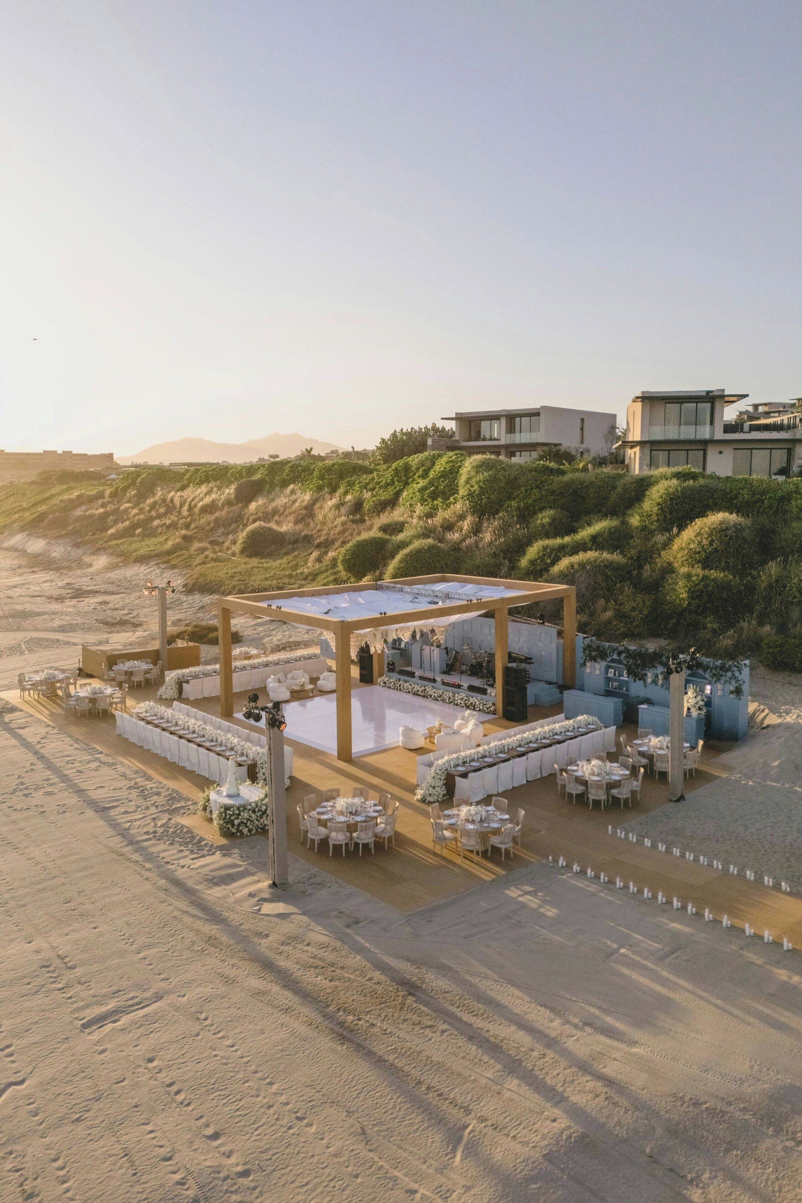 Un espacio para eventos frente a la playa, con un escenario, mesas y sillas dispuestas.