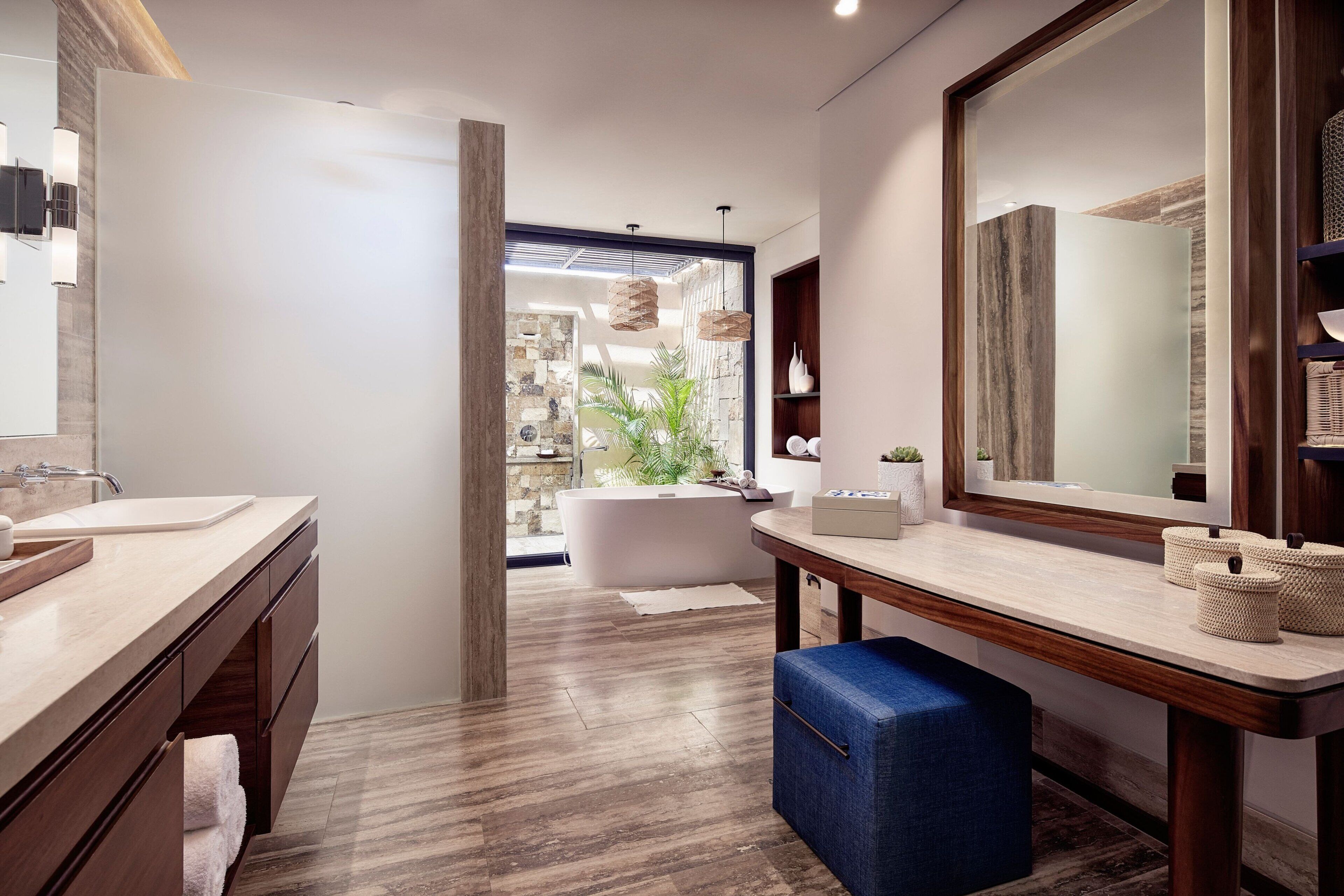 A modern bathroom with a large mirror, wooden vanity, and a bathtub.