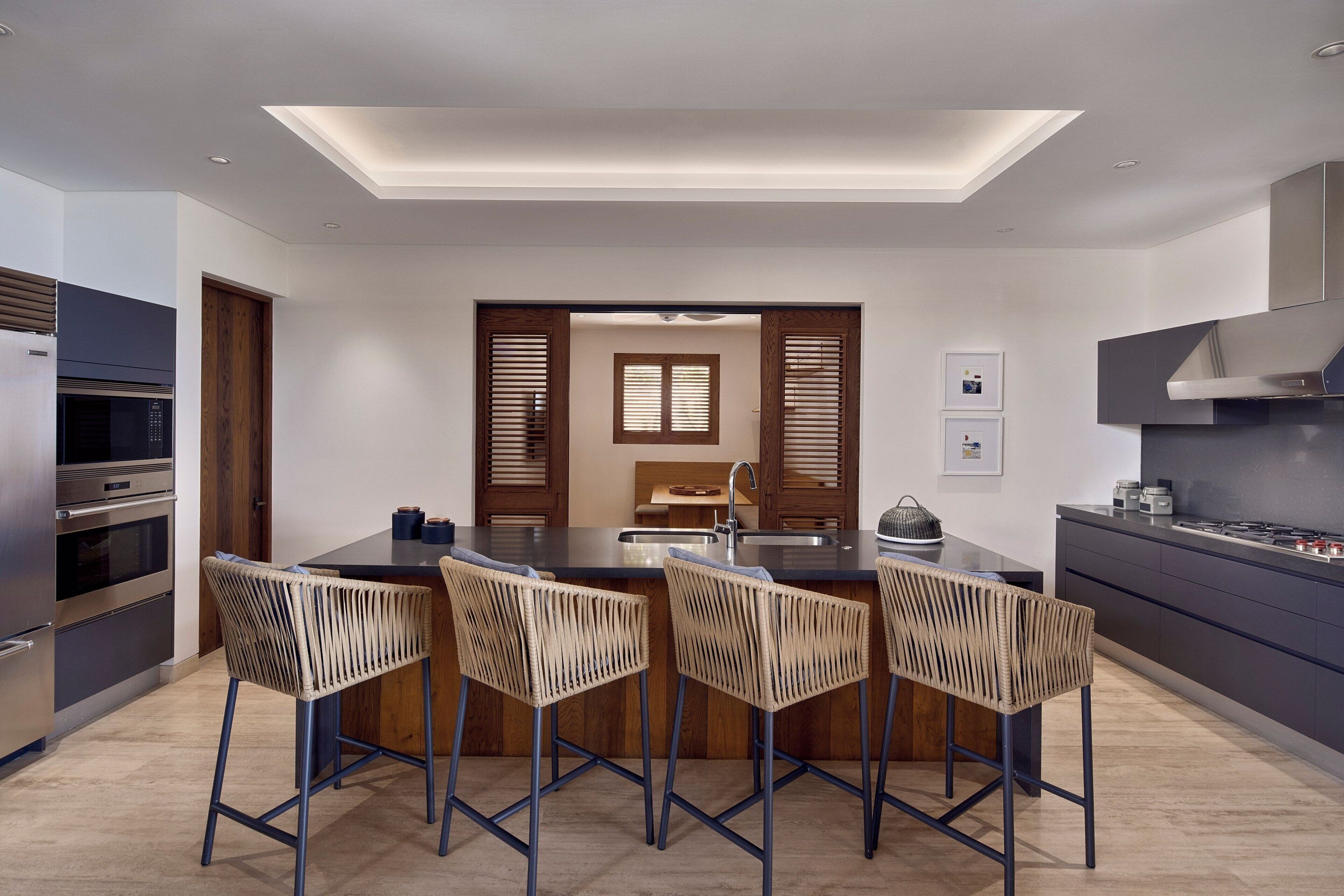 A modern kitchen with a central island, bar stools, built-in ovens, and a skylight.