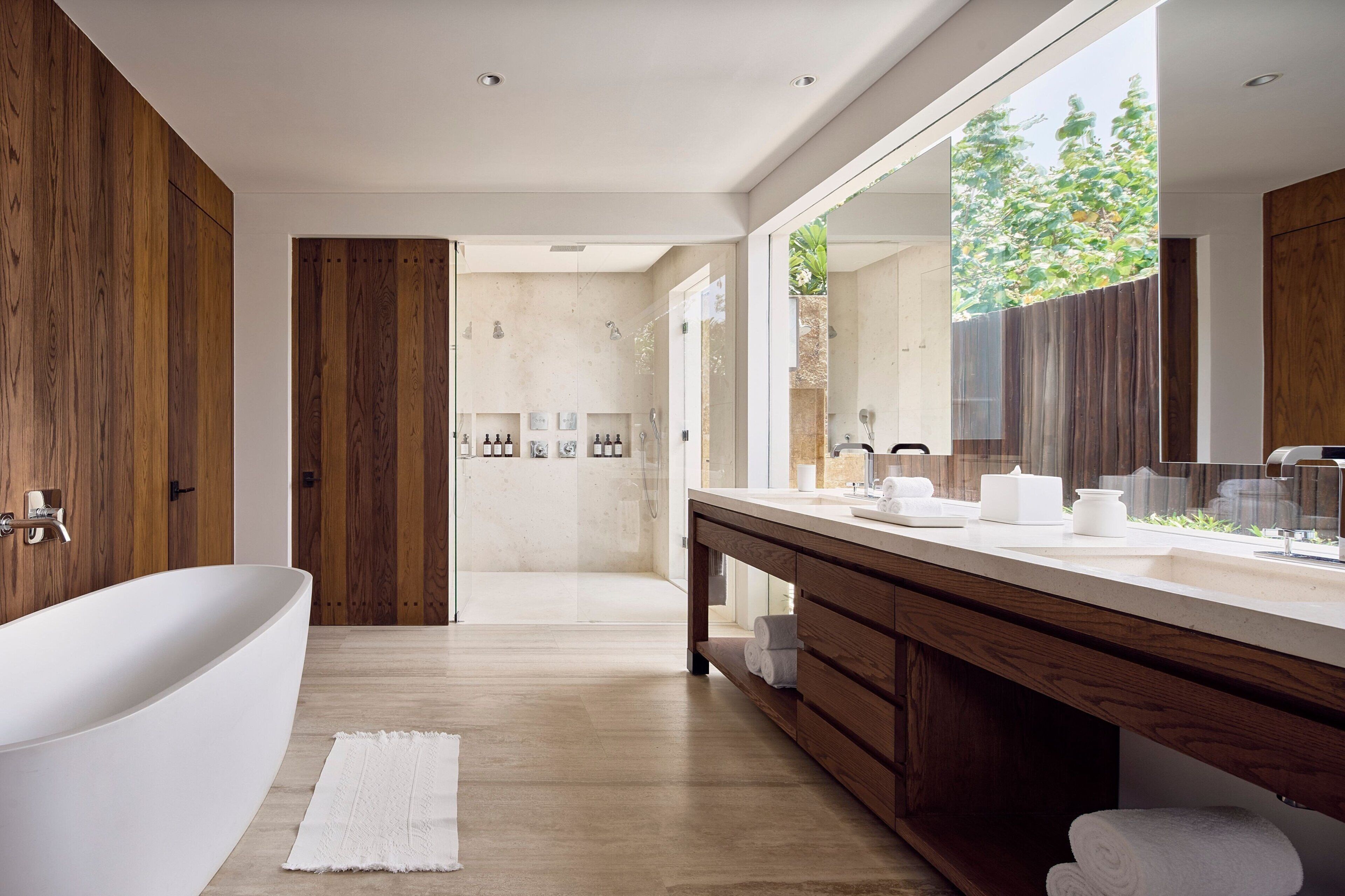 Un baño moderno con una bañera independiente, un espejo grande y una zona de ducha.