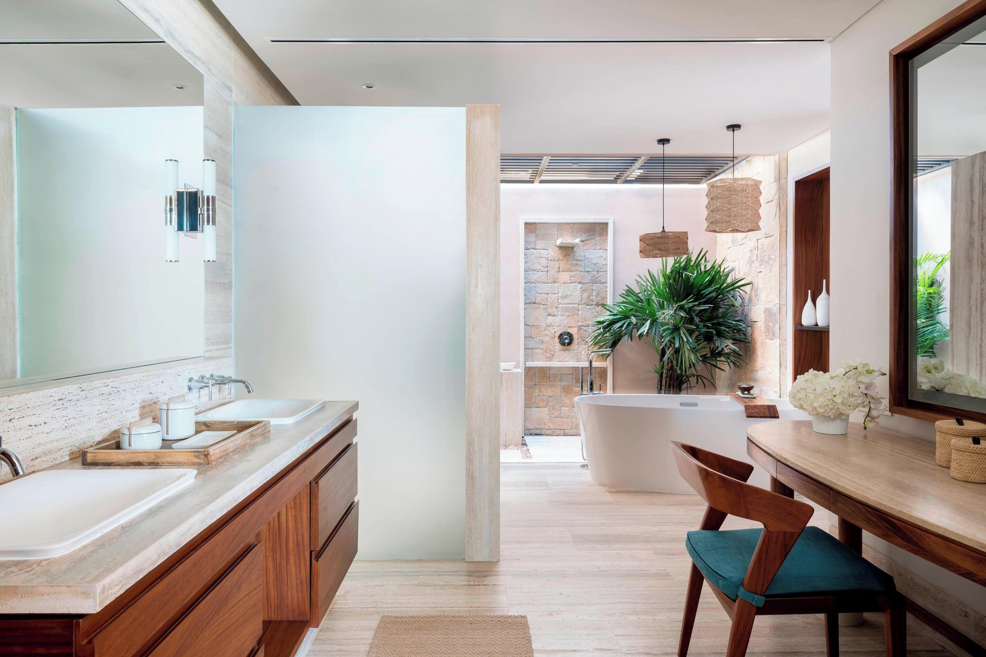 Un baño moderno con un espejo grande, lavamanos dobles, una bañera y un mueble de tocador de madera.