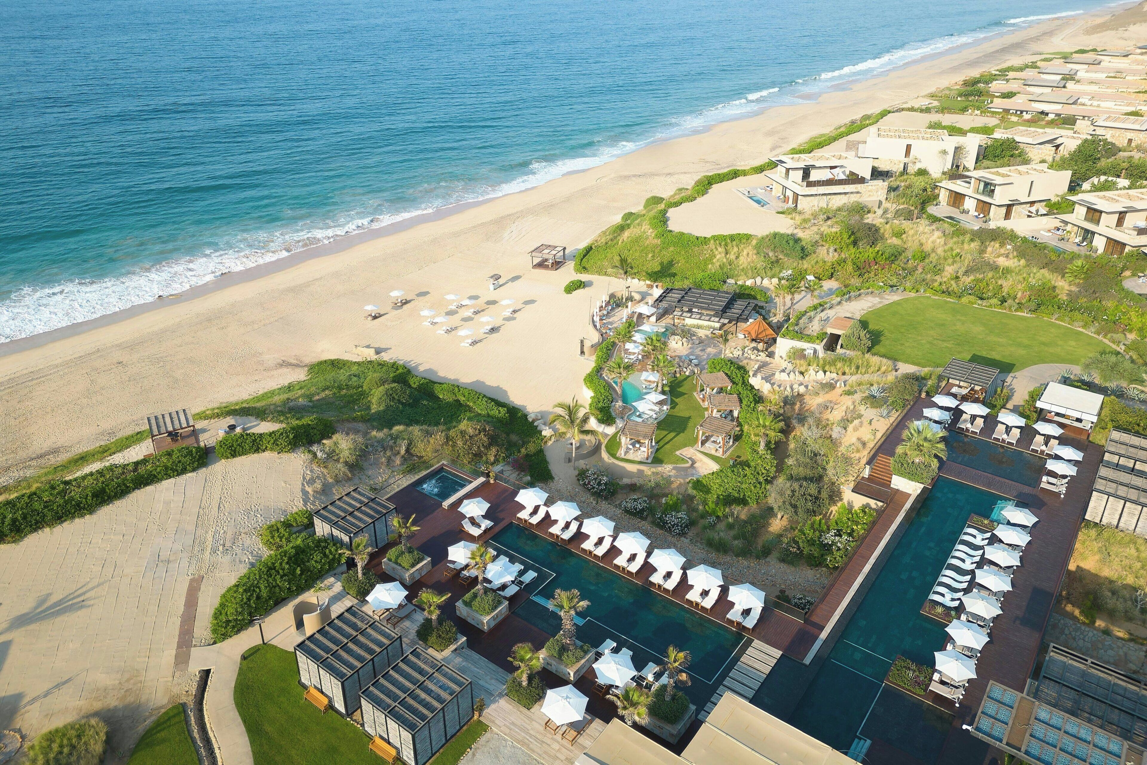Vue aérienne d’un complexe hôtelier doté d’une piscine, d’une plage et de nombreuses chambres.