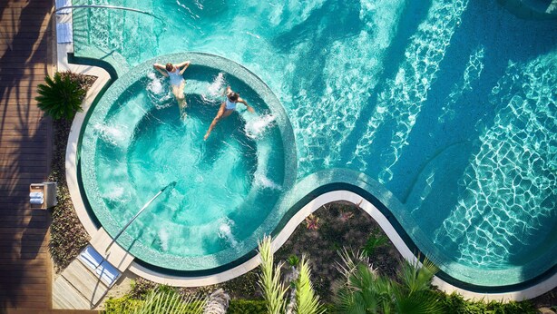 An aerial view of a circular swimming pool with two people in the center, surrounded by a wooden deck and greenery. - Zadun Los Cabos, a Ritz-Carlton Reserve (San José del Cabo)