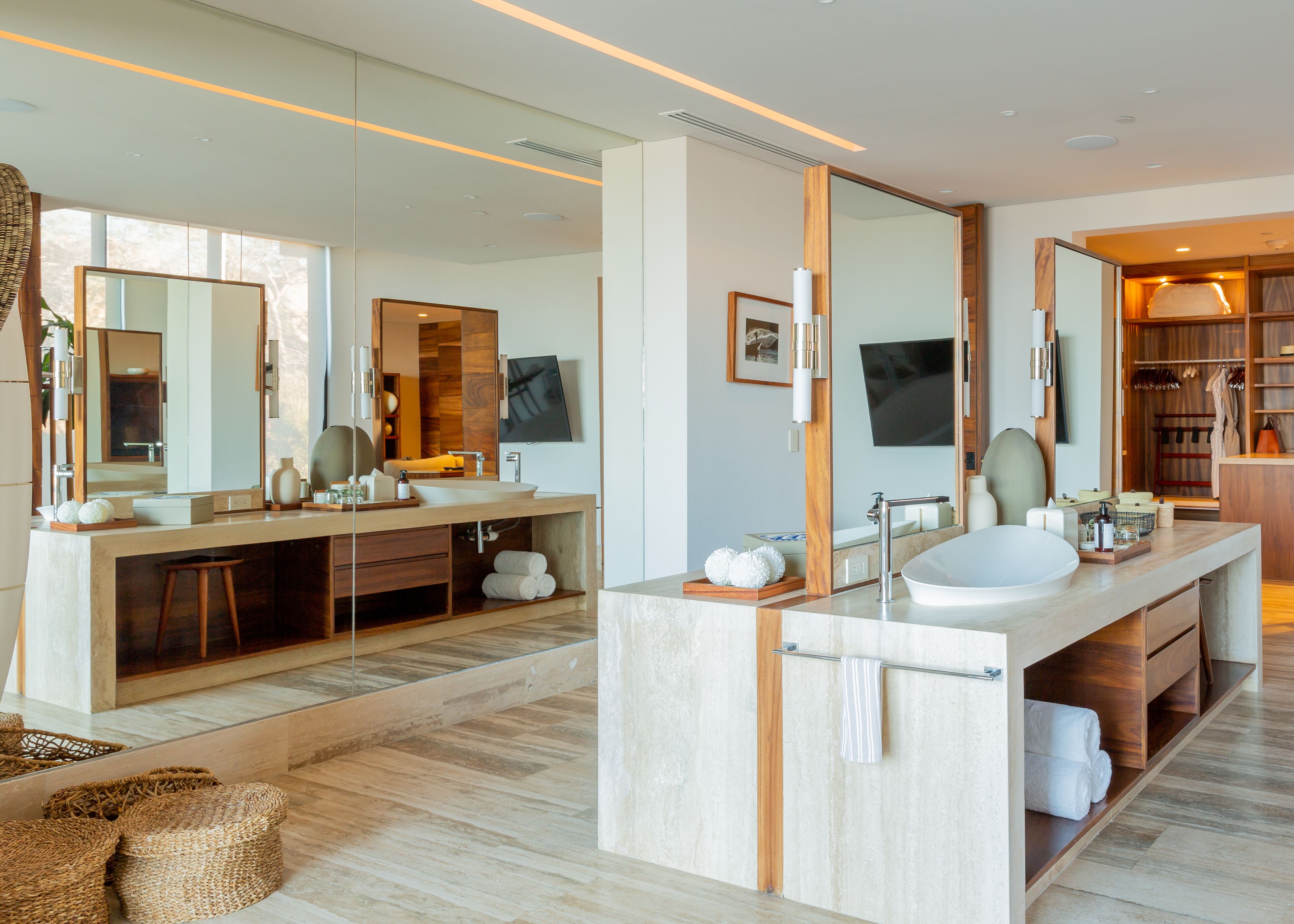 A modern bathroom with a large mirror, dual sinks, and a vanity with storage.