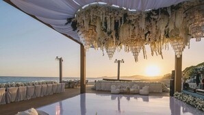 An outdoor seating area with white furniture and a view of the sunset over the ocean. - Zadun Los Cabos, a Ritz-Carlton Reserve (San José del Cabo)