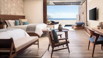 Une chambre d’hôtel avec un lit, un bureau, une chaise, une petite table et une vue sur la plage.