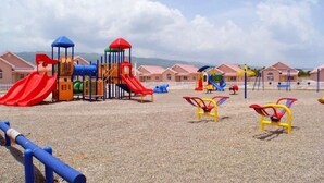 A playground with slides and climbing structures, surrounded by buildings with red roofs.