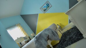 A room with a bed, a mirror, and a painting on the wall.