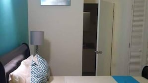 A bedroom with a bed, a wardrobe, a door, and a painting on the wall.