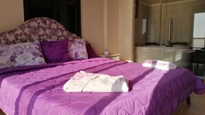 A bedroom with a large bed, a wardrobe, and a bathroom visible through an open door. - Quiet Comfy and Epic Seaview (Byblos)