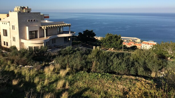 A modern building with a curved balcony overlooking a coastal view. - Quiet Comfy and Epic Seaview (Byblos)