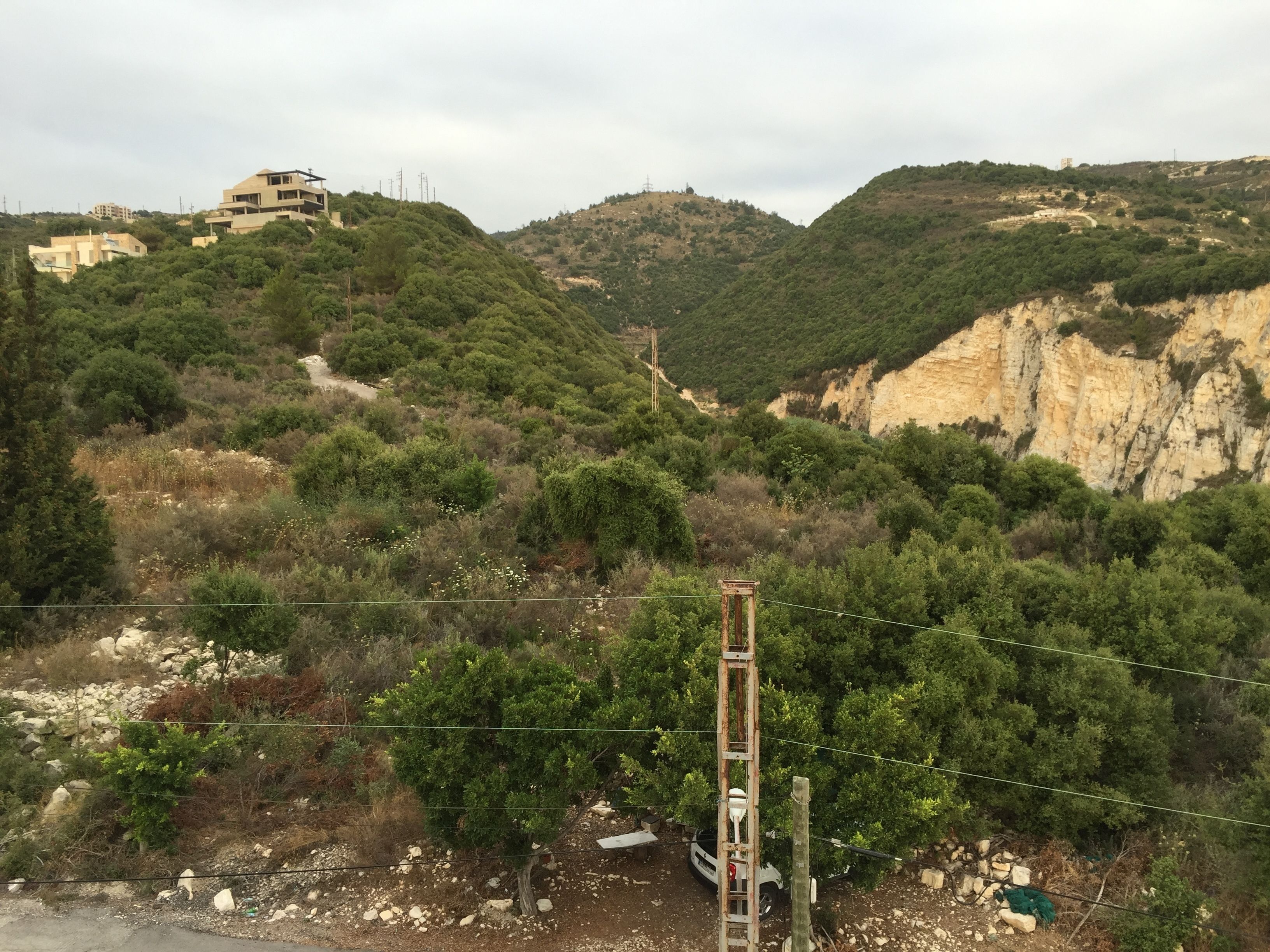 A mountainous landscape with buildings on the hills and a utility pole in the foreground.