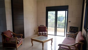 A room with a fireplace, two armchairs, a sofa, and a table. - Quiet Comfy and Epic Seaview (Byblos)