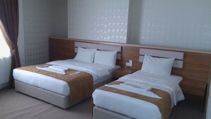 Ein Hotelzimmer mit zwei Betten, jeweils mit einem hölzernen Kopfstück und weißer Bettwäsche.
