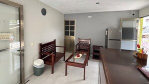 A compact kitchen with a refrigerator, a wooden chair, a small table, and a trash bin. - Hotel Villa Calakmul (Calakmul)