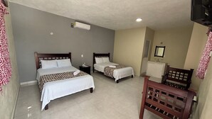 A hotel room with two beds, a wooden bench, a TV, and a ceiling fan. - Hotel Villa Calakmul (Calakmul)