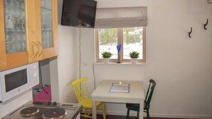 Cocina compacta con microondas, estufa y televisor montado en la pared.